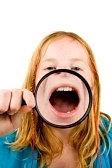 5912890-little-girl-is-showing-her-mouth-through-a-magnifying-glass-over-white